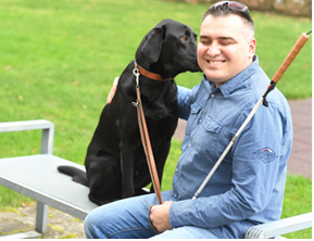 Valentino B. mit seinem Hund Dylan auf einer Parkbank sitzend.