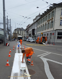 Strassenarbeiter tragen die weisse Farbe auf die Schablonen der Leitlinien auf.